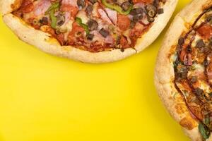 zwei anders köstlich groß Pizza auf ein Gelb Hintergrund foto