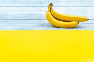 Gelb Bananen Lüge auf ein Blau hölzern Hintergrund und ein Gelb Hintergrund foto