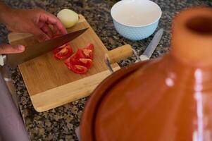 Aussicht von über von Hausfrau Hacken frisch organisch reif Tomaten auf ein hölzern Tafel während Kochen Abendessen beim Zuhause foto