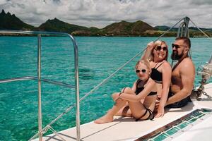 ein glücklich Familie im Badeanzüge sitzt auf ein Katamaran im das indisch Ozean. Porträt von ein Familie auf ein Yacht im das Koralle Riff von Mauritius foto