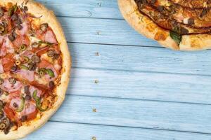 zwei anders köstlich groß Pizza auf ein Blau hölzern Hintergrund foto