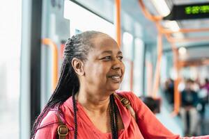 glücklich afrikanisch Senior Frau Reisen mit Öffentlichkeit Straßenbahn foto