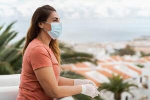 reifen Frau tragen medizinisch Gesicht Maske und Handschuhe Stehen auf Zuhause Terrasse - - Menschen Quarantäne zum verhindern und halt Corona Virus Verbreitung - - Gesundheitswesen und covid19 Beschränkung Konzept foto