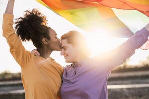 glücklich Lesben Paar haben romantisch Momente während halten Regenbogen Flagge draussen - - lgbt und Liebe Konzept foto