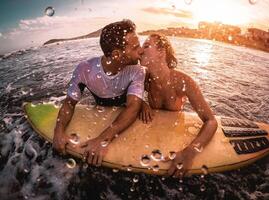 glücklich romantisch Paar küssen während Surfen im das Ozean - - sportlich Surfer körperlich haben ein zärtlich Moment im das Wasser - - extrem Sport, Liebe, Beziehung und gesund Lebensstil Konzept foto