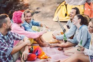 glücklich freunde haben Spaß Camping draussen - - jung Menschen Trinken Biere und spielen Gitarre im Campingplatz Nächster das Strand - - Jugend Kultur und Reise Ferien Konzept foto