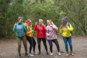 Gruppe von Frauen mit anders Alter und Ethnien haben ein komisch Moment Tanzen während ein gehen nebelig Wald - - Abenteuer und Reise Menschen Konzept foto