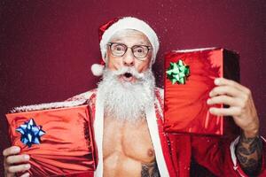 glücklich Santa claus halten Weihnachten die Geschenke - - Hipster bärtig Senior haben Spaß tragen Weihnachten Kleider feiern Ferien - - Alten modisch Menschen und traditionell Lebensstil Kultur foto