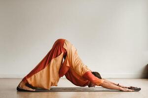 ein Mann im ein Orange passen tut Yoga im ein Fitness Zimmer. das Konzept von Gesundheit foto