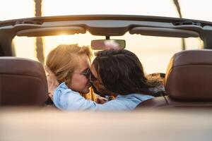 glücklich Paar küssen im Cabrio Auto - - romantisch Menschen haben zärtlich Moment während Straße Ausflug im tropisch Stadt - - Liebe Beziehung und Jugend Ferien Lebensstil Konzept foto