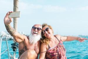 Senior Paar nehmen Selfie mit Handy, Mobiltelefon Smartphone auf Segelboot Ferien - - glücklich reifen Menschen haben Spaß feiern Hochzeit Jahrestag auf Boot Ausflug - - Liebe Beziehung und Reise Lebensstil Konzept foto