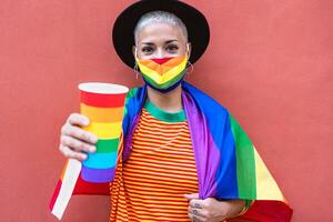 jung Frau tragen Fröhlich Stolz Maske und Regenbogen Flagge Symbol von lgbt Sozial Bewegung foto