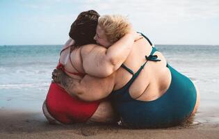 glücklich Plus Größe Frauen haben Spaß Umarmen auf das Strand während Ferien Sommer- Ferien - - kurvig zuversichtlich Menschen Lebensstil Konzept foto