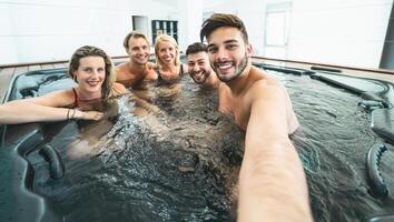 glücklich freunde nehmen Selfie während tun Whirlpool im Luxus Haus - - jung Menschen haben Spaß zusammen im heiß Wanne - - Jugend tausendjährig Generation und Wellness Lebensstil Ferien foto