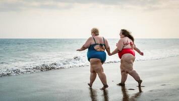 glücklich Plus Größe Frauen haben Spaß auf das Strand während Sommer- Ferien - - kurvig zuversichtlich Menschen Lebensstil Konzept foto