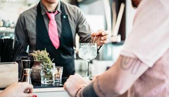 Barmann vorbereiten Gin Tonic Cocktail - - Menschen haben Spaß im amerikanisch Bar warten zum Barmann Portion Getränke - - Konzept von Jugend Lebensstil und Bar Unterhaltung foto