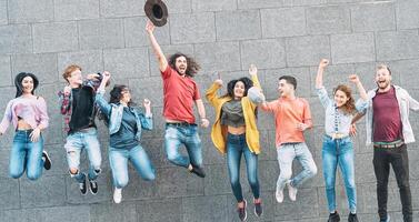 Gruppe von jung Menschen Springen zusammen draussen - - glücklich tausendjährig freunde feiern Erfolg im Hochschule - - Jugend Kultur Lebensstil und Freundschaft Konzept foto