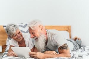 glücklich Senior Paar mit Digital Tablette im Bett - - reifen Menschen haben komisch Bett Zeit zusammen - - Alten Liebe Beziehung Lebensstil und Technologie Konzept foto