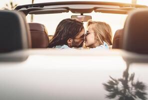 glücklich Paar küssen im Cabrio Auto - - romantisch Menschen haben zärtlich Moment während Straße Ausflug im tropisch Stadt - - Liebe Beziehung und Jugend Ferien Lebensstil Konzept foto