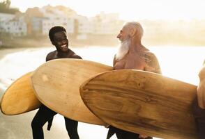 glücklich passen Surfer mit anders Alter und Rennen haben Spaß während Surfen Tag auf das Strand beim Sonnenuntergang Zeit - - extrem Sport Lebensstil und Freundschaft Konzept foto