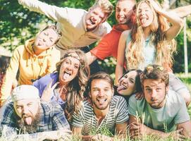 Gruppe von freunde haben Spaß zusammen Lügen auf Gras während Herstellung ein selbst Porträt mit dumm Gesichter - - jung glücklich Menschen nehmen Foto von Gruppe beim Picknick Camping Park - - Freundschaft und Lebensstil Konzept