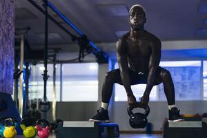 jung afrikanisch Mann Ausbildung Innerhalb Fitnessstudio - - passen schwarz männlich tun Kessel Glocke Übung trainieren Session im Sport Verein Center - - Sport Lebensstil Konzept foto