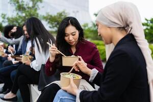 gemischtrassig Geschäft Menschen nehmen ein brechen Essen ein Mahlzeit draußen das Büro foto