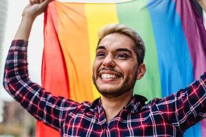 glücklich Fröhlich Mann feiern Stolz Festival halten Regenbogen Flagge Symbol von lgbtq Gemeinschaft foto