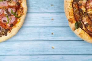 zwei anders köstlich groß Pizza auf ein Blau hölzern Hintergrund foto
