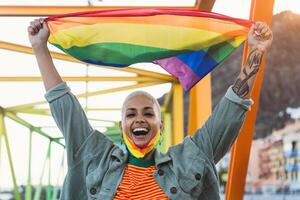 jung Frau feiern Fröhlich Stolz halten Regenbogen Flagge Symbol von lgbtq Gemeinschaft foto