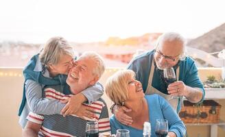 glücklich Senioren Paar haben Spaß Essen zusammen auf Terrasse - - romantisch älter Menschen Trinken Wein und genießen ein sonnig Tag auf Dach - - Freundschaft, Pensionierung und Alten Lebensstil Aktivitäten Konzept foto