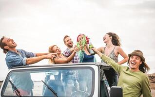 Gruppe von glücklich freunde Herstellung Party auf Cabrio Auto - - tausendjährig jung Menschen haben Spaß Trinken Champagner während Straße Ausflug - - Freundschaft, Urlaub, Jugend Ferien Lebensstil Konzept foto
