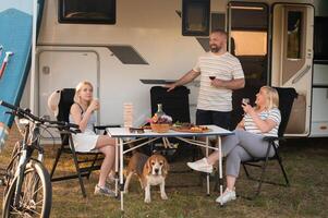 ein glücklich Familie ist ruhen in der Nähe in der Nähe von ihr Wohnmobil im das Wald foto