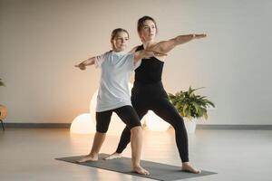 Mama und Teenager Tochter tun Gymnastik zusammen im das Fitness Zimmer. ein Frau und ein Mädchen Zug im das Fitnessstudio foto