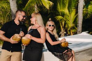 ein stilvoll Familie im schwarz Kleider mit Kokosnüsse im ihr Hände auf das Strand von das Insel von mauritius.schön Familie auf das Insel von Mauritius im das indisch Ozean foto