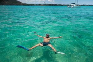 ein Kerl im Flossen und ein Maske schwimmt im ein Lagune auf das Insel von Mauritius foto