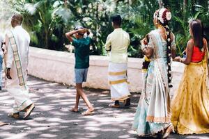 unkenntlich Einheimische im traditionell Outfits gehen durch das Park von das Insel von Mauritius, traditionell Hochzeit Kleider auf das Menschen von Mauritius foto