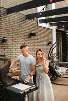 ein verheiratet Paar Köche gegrillt Fleisch zusammen auf ihr Terrasse foto