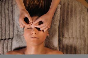 ein Kosmetikerin Mädchen tut ein Gesichts- und Hals Massage zu ein Mädchen im das Büro zum Haut Elastizität foto
