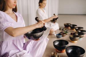 zwei weiblich Yoga Lehrer abspielen auf tibetanisch Schalen im das Fitnessstudio während ein Yoga Rückzug foto