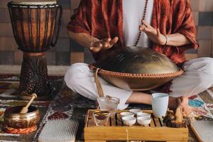 Nahansicht von ein des Mannes Hand spielen ein modern Musical Instrument - - das Orion Zunge Trommel während das Tee Zeremonie foto