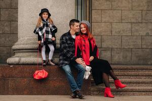 ein stilvoll Familie von drei Spaziergänge durch das Herbst Stadt posieren zum ein Fotograf . Papa, Mama und Tochter im das Herbst Stadt foto