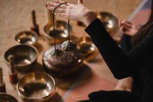 Nahansicht von ein Frau Hand halten tibetanisch Glocken zum Klang Therapie. tibetanisch Becken foto