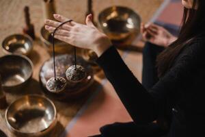 Nahansicht von ein Frau Hand halten tibetanisch Glocken zum Klang Therapie. tibetanisch Becken foto