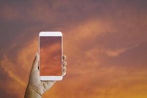 Hand halt Clever Telefon mit Wolke beim Sonnenuntergang foto