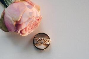 Designer Hochzeit Ringe Lügen auf das Oberfläche mit ein Rose. zwei Hochzeit Ringe foto