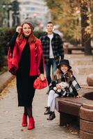 ein stilvoll Familie von drei Spaziergänge durch das Herbst Stadt posieren zum ein Fotograf . Papa, Mama und Tochter im das Herbst Stadt foto