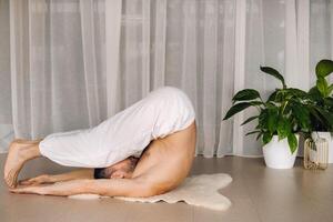 ein Mann mit ein nackt Torso tut Yoga im ein Fitness Zimmer. das Konzept von ein gesund Lebensstil foto
