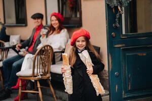 ein stilvoll Mädchen mit Baguettes steht in der Nähe von das Geschäft gegen das Hintergrund von ihr Eltern foto