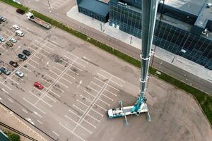 Aussicht von das Höhe von das Auto schwer Kran Das steht öffnen im das Parkplatz Menge und bereit zu arbeiten. das höchste LKW Kran ist bereitgestellt auf das Seite? ˅. das Höhe von das Boom ist 80 Meter foto